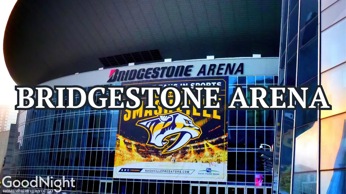 Exterior view of Bridgestone Arena, featuring a large glass facade, prominent arena signage, and a visible Nashville Predators banner. The area is buzzing with people, capturing the excitement of events and live concerts.