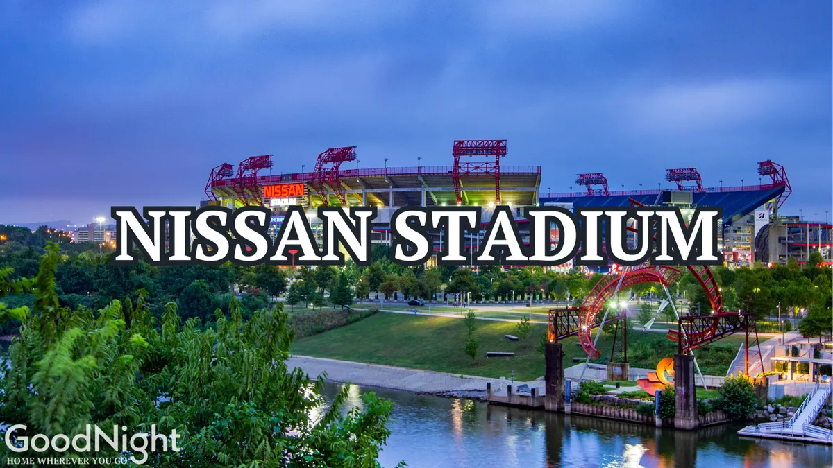 This image captures Nissan Stadium from an exterior perspective, surrounded by a lively park area and the nearby river. The stadium's iconic architecture is visible, and the setting suggests excitement and anticipation for major sporting events. The vibrant mood is accentuated by people gathering and the possibility of sunset lighting over the venue.