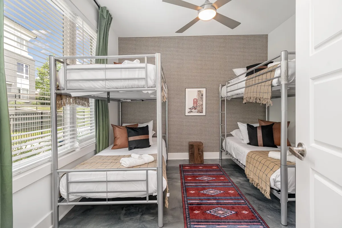 A family-friendly bedroom with cozy bunk beds, a decorative rug, and cheerful artwork, basking in natural light. The space feels playful and inviting, ideally suited for children or group stays, and subtly suggests pet- and kid-friendly policies.