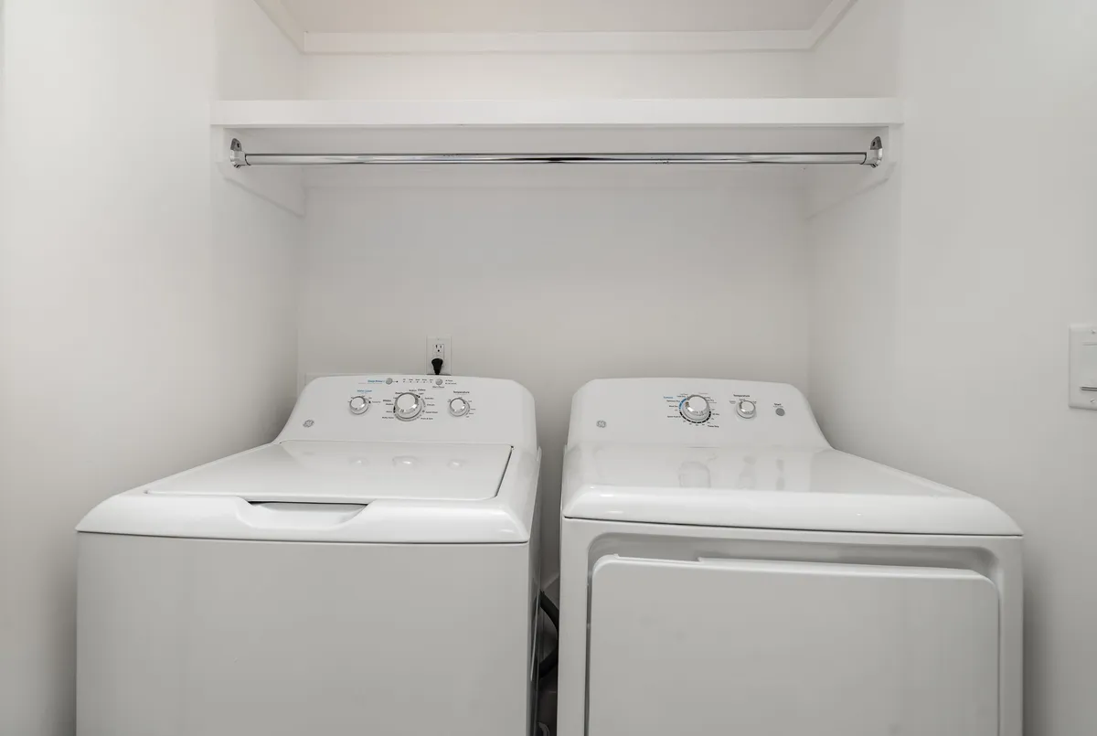 A dedicated laundry area featuring a washing machine, dryer, and shelving for supplies. The setup is neat and organized, emphasizing practicality and convenience for guests staying longer or traveling with families.
