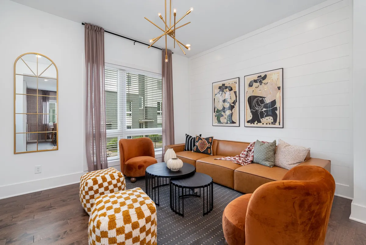 This image showcases a chic and inviting living room with a modern sofa, eye-catching artwork, a decorative mirror, and stylish lighting. The space exudes a blend of urban flair and western charm, perfect for relaxing, socializing, or unwinding with friends and family.