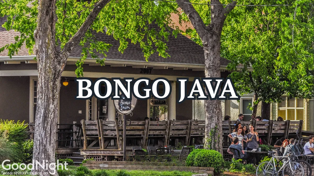 An exterior shot featuring the signage for 'Bongo Java,' a beloved local coffee shop, surrounded by trees and an inviting seating area. The lively atmosphere is captured by people enjoying coffee and conversation outdoors.