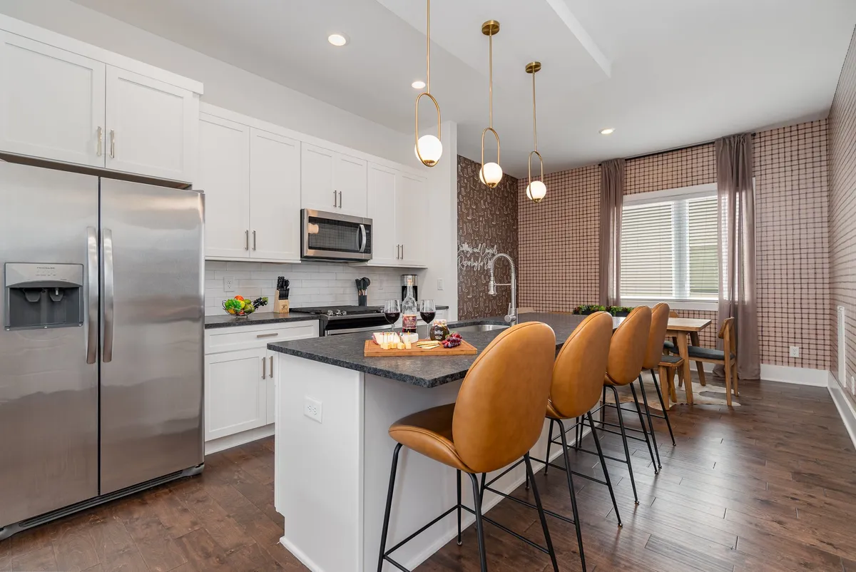 A stylish kitchen and dining area with a central island, barstools, and a window adorned with curtains. The open layout encourages socializing and casual meals, while the modern fixtures and tasteful decor reflect the thoughtful amenities and attention to guest needs.